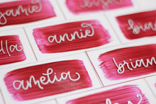 Load image into Gallery viewer, Acrylic place cards with hand-lettered names and rose-coloured painted backs. 
