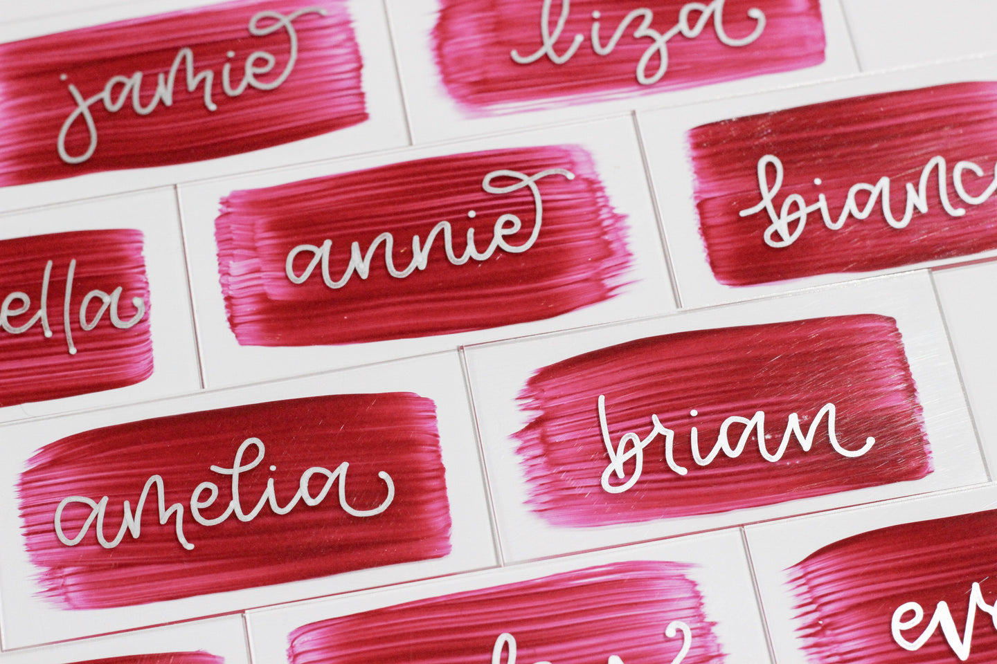 Acrylic place cards with hand-lettered names and rose-coloured painted backs. 